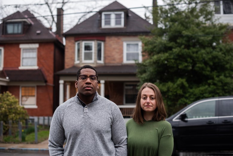 Maddie Gioffre (right) and Shaquille Charles stand in front of their Wilkinsburg home on April 5, 2022. The two purchased the home in early 2020 and were promptly subjected to an assessment appeal. They are the lead plaintiffs in a lawsuit challenging the way Allegheny County calculates property assessments after appeals. (Photo by Lindsay Dill/PublicSource)