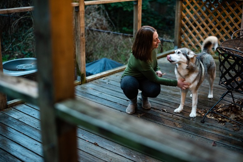 Maddie Gioffre and Royce, one of her household's two dogs, play outside at their Wilkinsburg home. (Photo by Lindsay Dill/PublicSource)