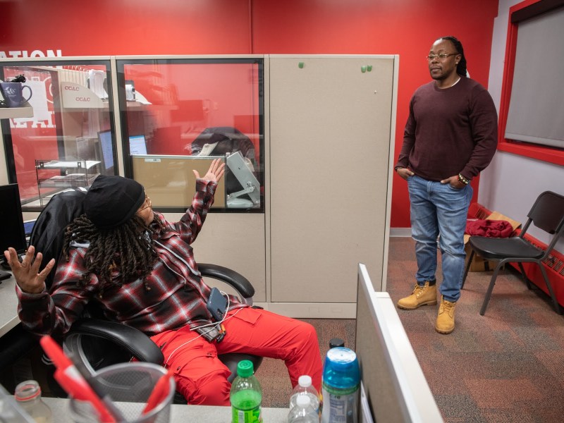 Amber Sloan, left, and Michael Talley talk in their office at the Community College of Allegheny County Homewood-Brushton Center where they are community success coaches, on Tuesday, Dec. 6, 2022, in Homewood South. Sloan and Talley use their own life experience and knowledge of the community to help others connect with support and resources available to both prevent and respond to the impacts of gun violence. (Photo by Stephanie Strasburg/PublicSource)