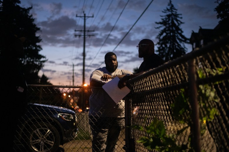 Godfrey McCray, project manager with Greater Valley Community Services (GVCS) violence prevention team, and Lee Davis, director of violence prevention for GVCS, talk after a meeting of the Greater Valley Coalition Against Violence on Tuesday, Aug. 29, 2023, as the sun sets in Braddock. Davis has helped implement the Cure Violence model in Pittsburgh over the past four years, which trains trusted community figures to serve as “credible violence interrupters” tasked with connecting at-risk individuals with support and services. (Photo by Stephanie Strasburg/PublicSource)