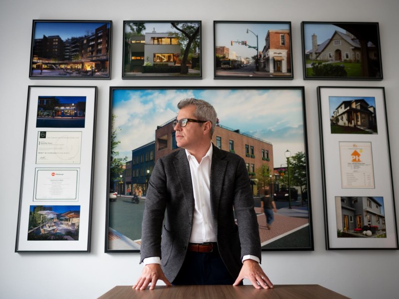 man stands at a desk in front of photo gallery