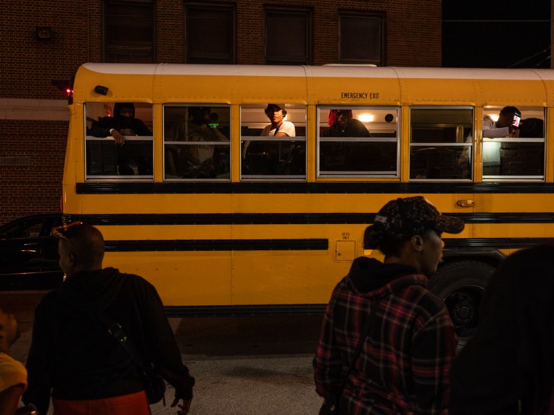 A group of people waiting to get on a school bus.