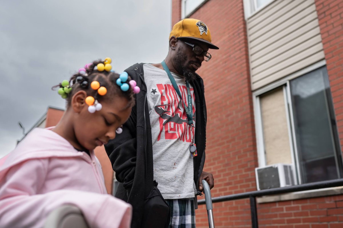 Hi View Gardens tenant Santaris Porter, right, and his daughter, Avry Hays, 5, listen during a tenant council meeting outside Hi View on Tuesday, Sept. 26, 2023, in McKeesport. ”We have the big pest problem here and I want to see that addressed,” said Porter, who has lived at the apartment complex for a year and a half. (Photo by Stephanie Strasburg/PublicSource)