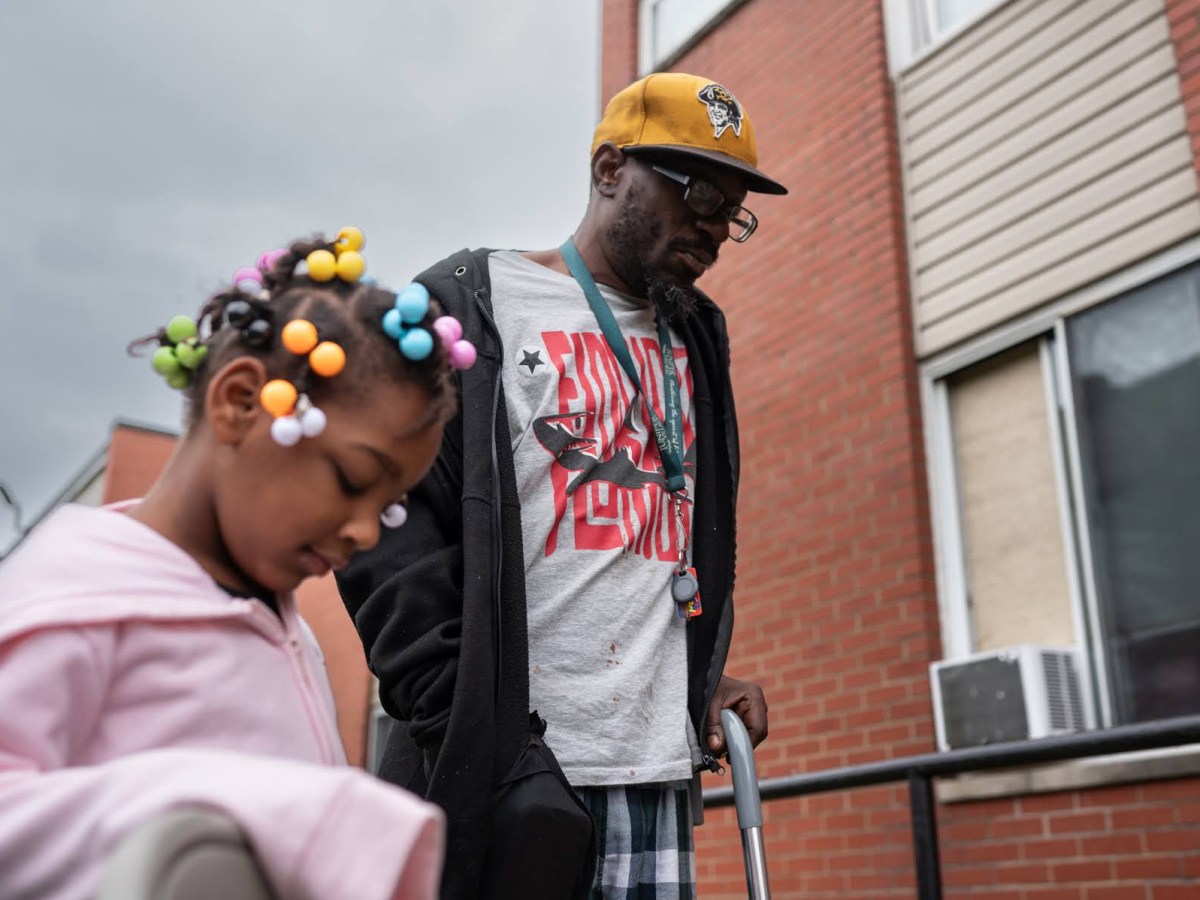 Hi View Gardens tenant Santaris Porter, right, and his daughter, Avry Hays, 5, listen during a tenant council meeting outside Hi View on Tuesday, Sept. 26, 2023, in McKeesport. ”We have the big pest problem here and I want to see that addressed,” said Porter, who has lived at the apartment complex for a year and a half. (Photo by Stephanie Strasburg/PublicSource)