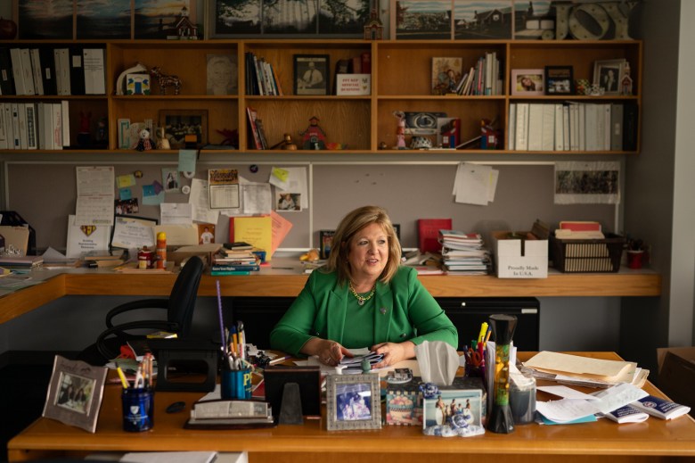 Nina Esposito-Visgitis, president of the Pittsburgh Federation of Teachers, at the union offices in the South Side Flats on Thursday, Oct. 19, 2023. She sits at a desk and looks towards the window to her left. In shelves around her, mementos from her years in the industry include photos, figurines, and files, among other things. (Photo by Stephanie Strasburg/PublicSource)