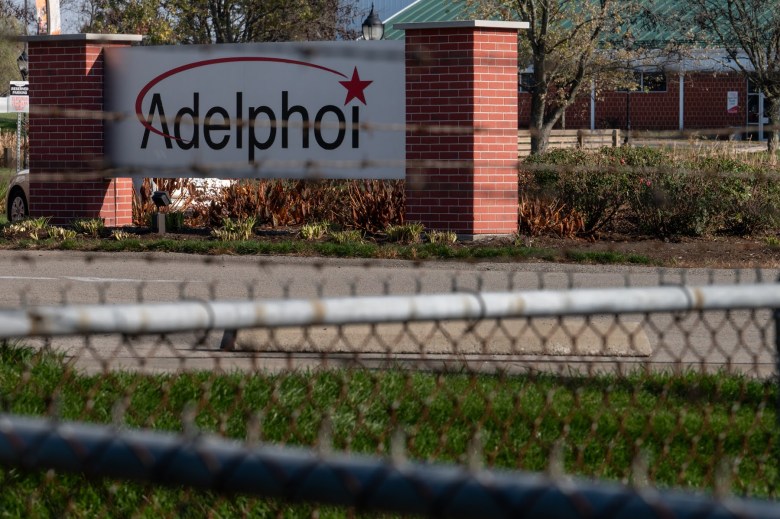 A white "Adelphoi" sign is seen beyond a chain link fence at Adelphoi Village in Latrobe.