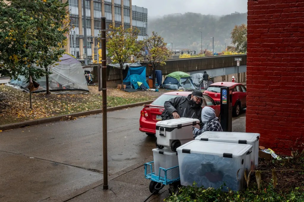 Muhammad Ali Nasir, also known by his emcee name MAN-E, the advocacy & policy, civic engagement coordinator for 1Hood and founder of Community Care & Resistance In Pittsburgh (CCRIP), loads up after distributing supplies at the encampment along First Avenue and Boulevard of the Allies on a rainy Sunday, Oct. 29, 2023, in Downtown Pittsburgh. “We’re getting requests for sleeping bags, hats, coats, and folks are preparing to sleep outside during the colder months,” said Nasir. (Photo by Stephanie Strasburg/PublicSource)