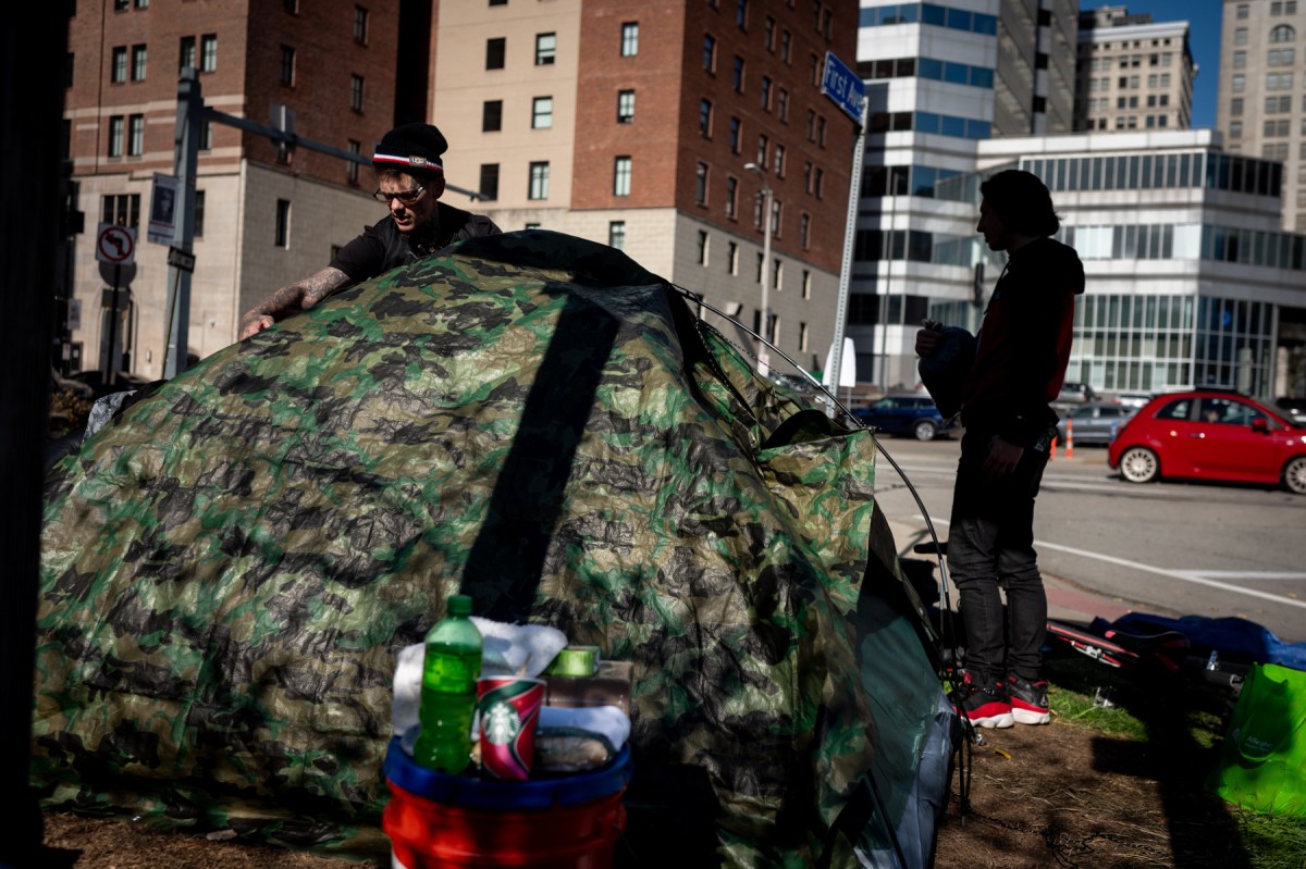 A person experiencing housing instability sets up a new tent for himself and his partner after packing up their belongings to move in accordance with the city's closure of the First Avenue encampment, where they were staying on Monday, Nov. 6. (Photo by Stephanie Strasburg/PublicSource)