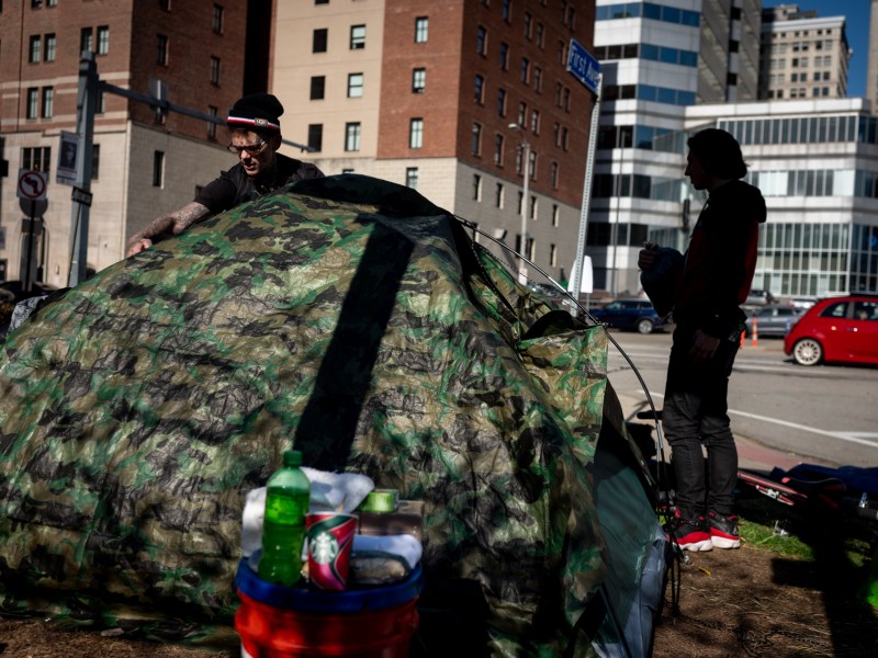 A person experiencing housing instability sets up a new tent for himself and his partner after packing up their belongings to move in accordance with the city's closure of the First Avenue encampment, where they were staying on Monday, Nov. 6. (Photo by Stephanie Strasburg/PublicSource)