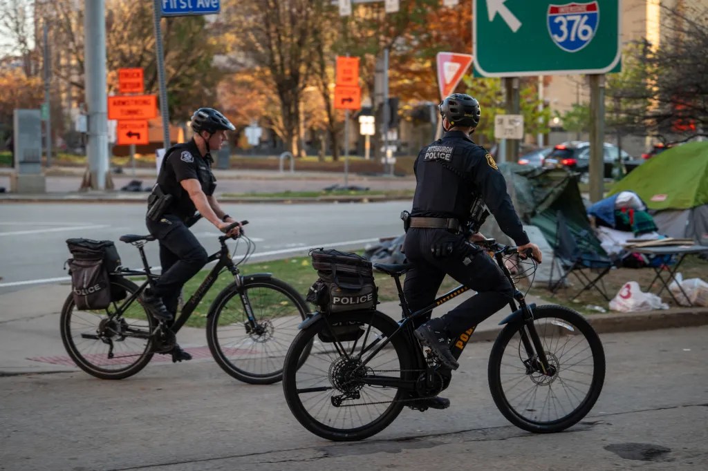 Police approach the First Avenue encampment leading up to the 5 p.m. deadline when the site was to be cleared, on Tuesday, Nov. 7, 2023, in downtown Pittsburgh. The city planned to close the encampment by 5 p.m. that day, but pushed the closing off to the next day to buy more time to place people in alternative shelter. (Photo by Stephanie Strasburg/PublicSource)