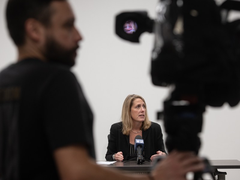 Erin Dalton, director at Allegheny County Department of Human Services (ACDHS), is seen through a news camera as she speaks to the press about the county’s plans for winter shelter and other services for people who are unhoused on Wednesday, Nov. 15, 2023, at ACDHS headquarters in Downtown Pittsburgh. (Photo by Stephanie Strasburg/PublicSource)