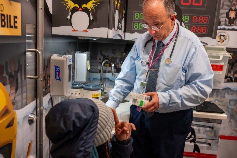 A man in a suit is giving a child medicine.