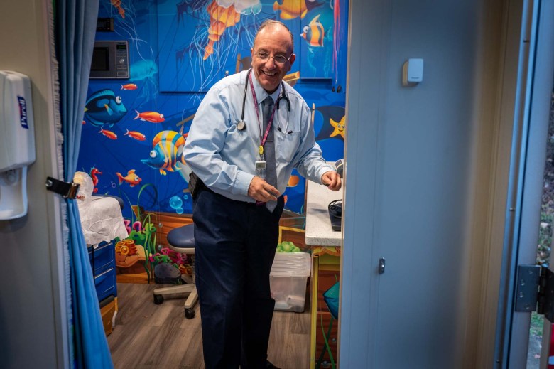 A man standing in the doorway of a patient area decorated with aquatic art.