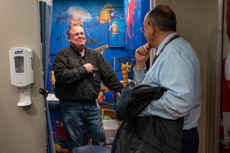 A man in a blue shirt talking to a doctor in a blue shirt.