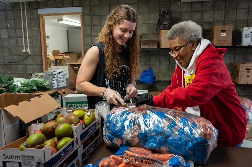 Two women volunteers unpack produce at the Oakland Food Pantry.