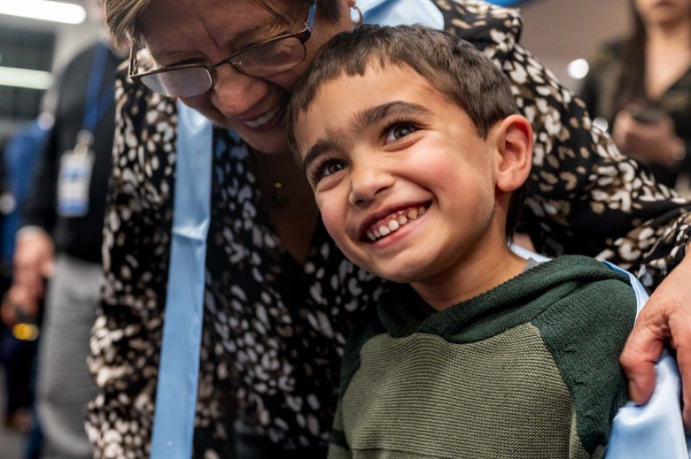 A woman hugs a young boy.