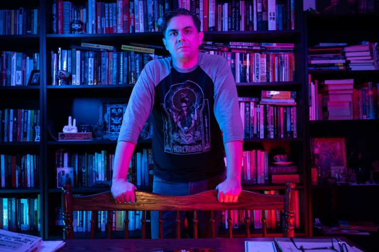 A man standing in front of a book shelf.
