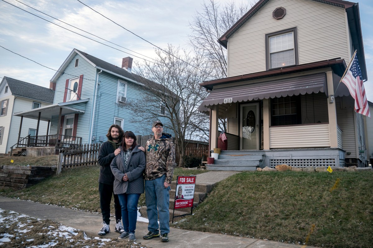 three people stand in front of a house
