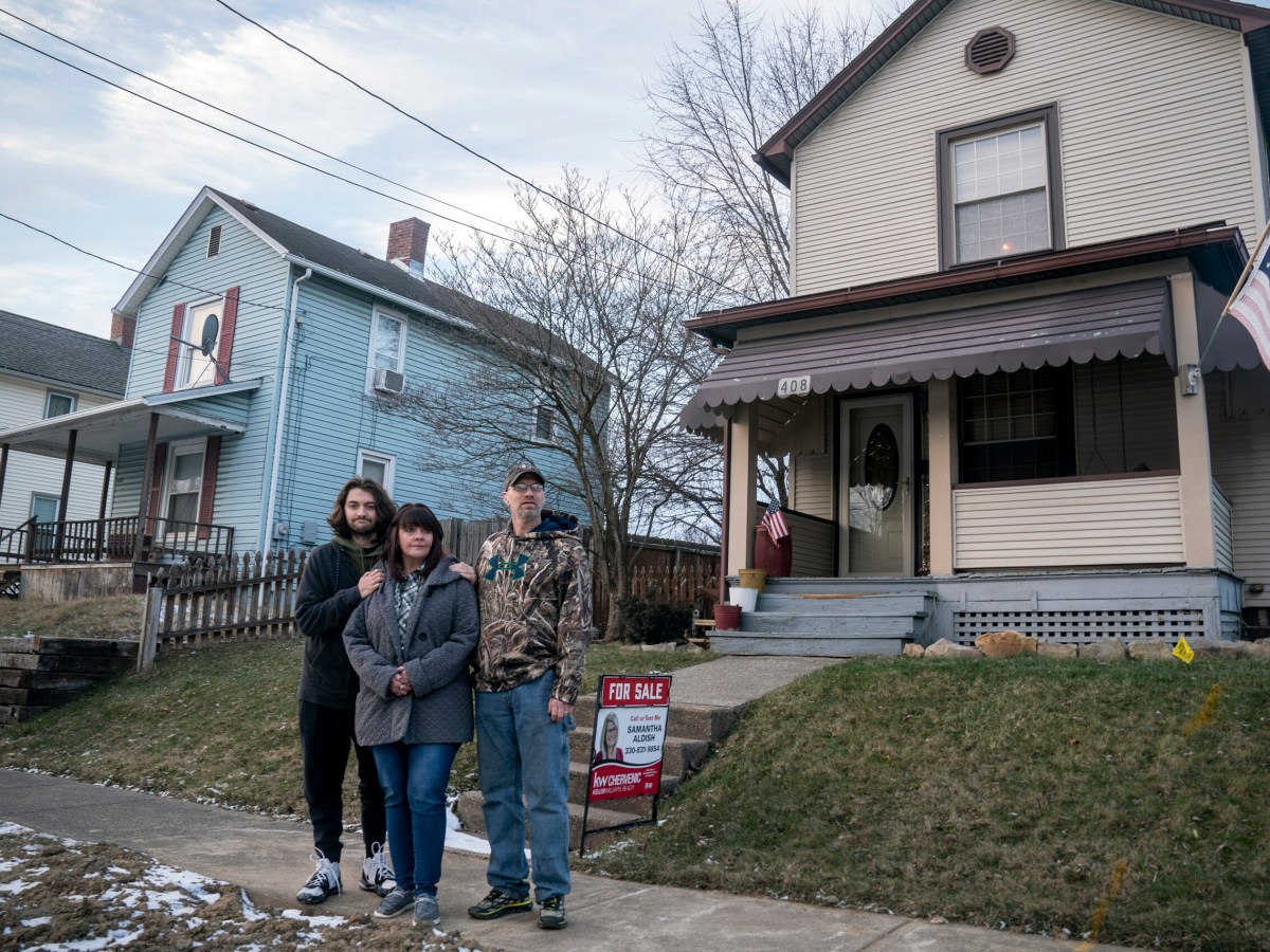three people stand in front of a house