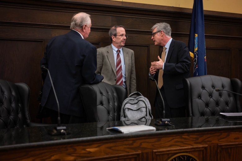 Three men standing around a table in a courthouse room.