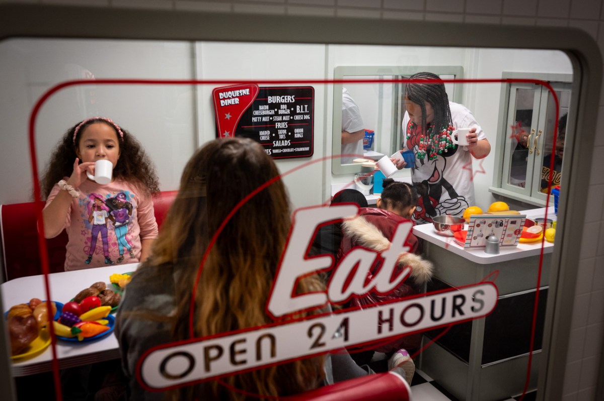 A group of people sitting at a table in a pretend diner.