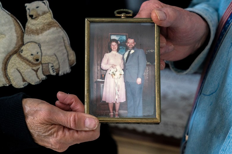 A woman holds up a photo of a bride and groom.