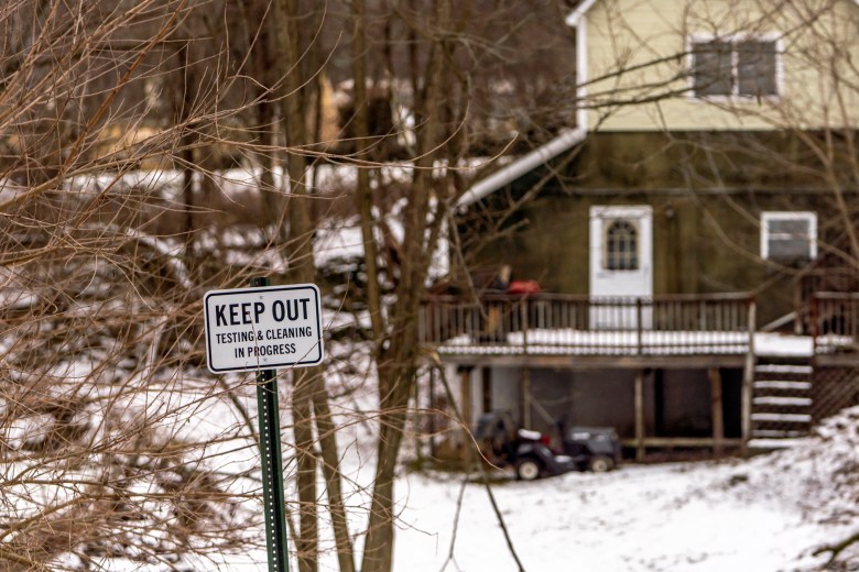 A keep out sign posted to a tree in front of a house.