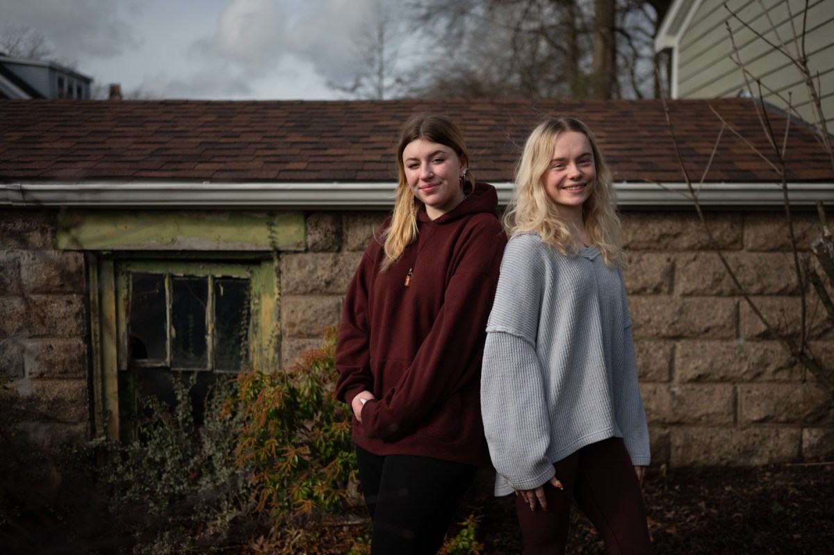 Two young women standing in front of a house.
