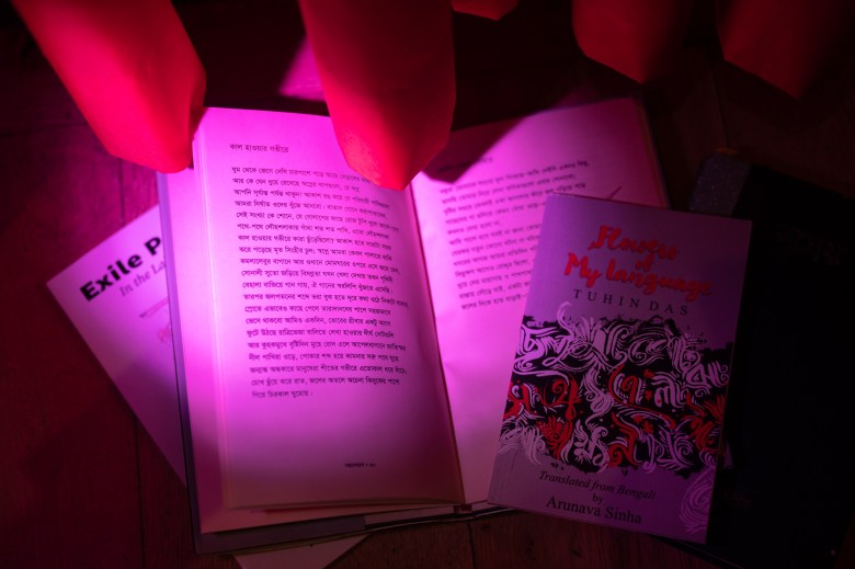 Books open on a table under a pink light.