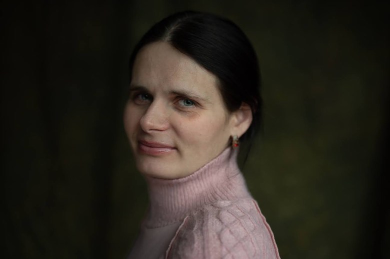 A woman in a pink turtleneck posing for a photo.