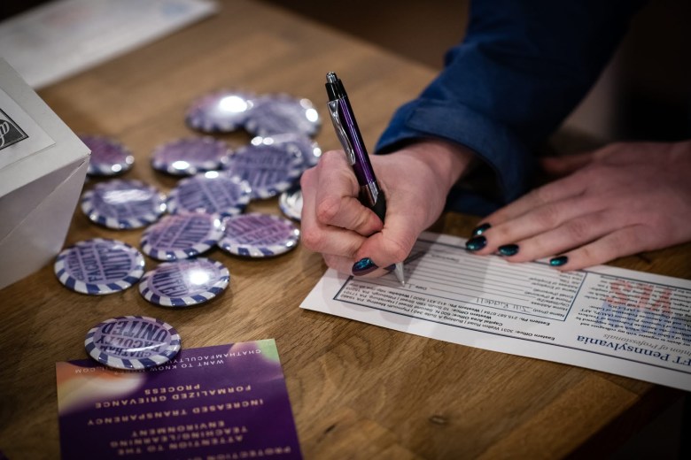 A person signing a form at a table with buttons.