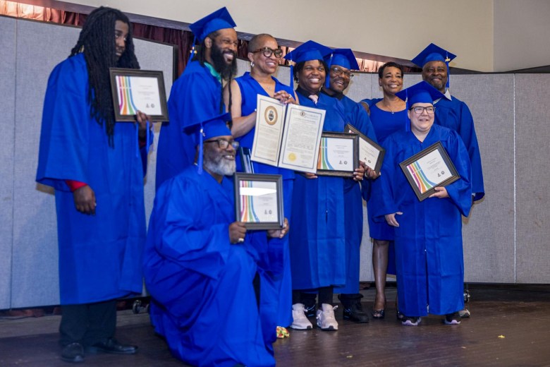 A group of nine people in blue robes holding certificates.