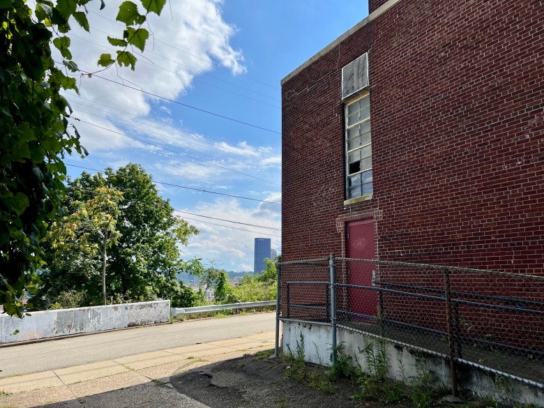 The side entrance of the Cowley Rec Center, with its locked doors and broken windows, with Downtown's skyscrapers in the background