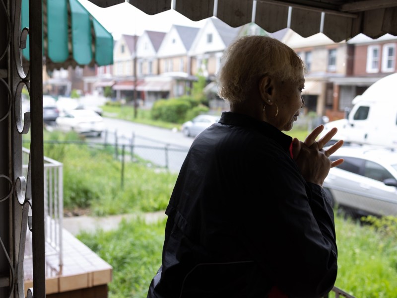 Tanya Todd stands on the front porch of her North Homewood house in the spring rain. Two years ago that would've meant sewer backups and property tax bills. (Photo by Benjamin Brady/PublicSource)