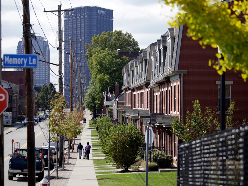 People walk along Bedford Avenue near the Bedford Hill Apartments in Pittsburgh’s Hill District. The Housing Authority of the City of Pittsburgh is trying to secure more low-income housing in the city. (Photo by Ryan Loew/PublicSource)