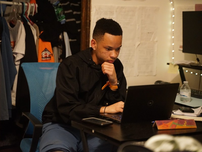 Sean Russell takes notes on his computer after a scholarship interview over Zoom in his bedroom. (Photo by Oliver Morrison / PublicSource)