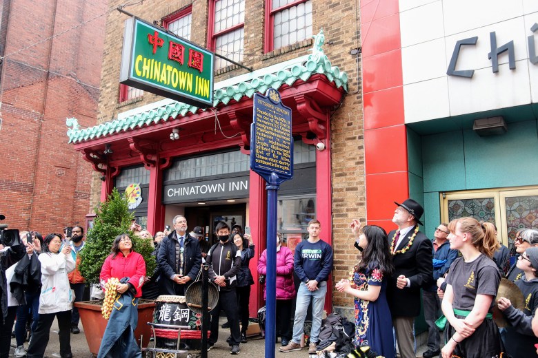 A crowd of people in front of the Chinatown Inn look up at the historical marker for Pittsburgh's Chinatown.