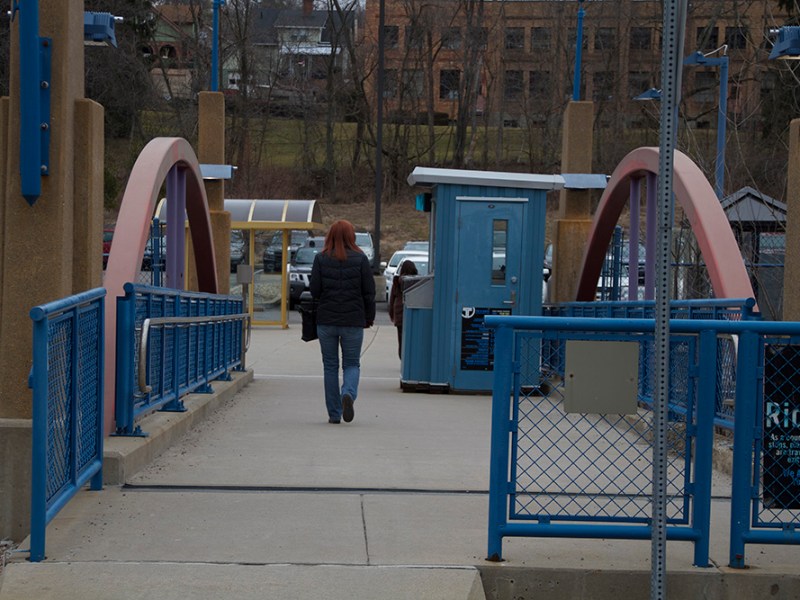 A public transit rider walks from the Pittsburgh Regional Transit Blue Line's Library T Station to the park and ride lot.