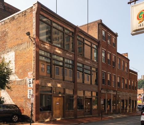 A car is parked in front of a brick building.