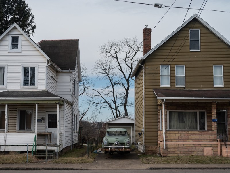 An old car sits on blocks between two McKeesport homes on Monday, Feb. 13, 2023. (Photo by Stephanie Strasburg/PublicSource)