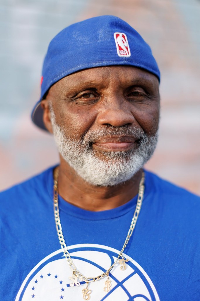 Richard Garland is wearing a blue baseball cap and a blue 76ers T-shirt.