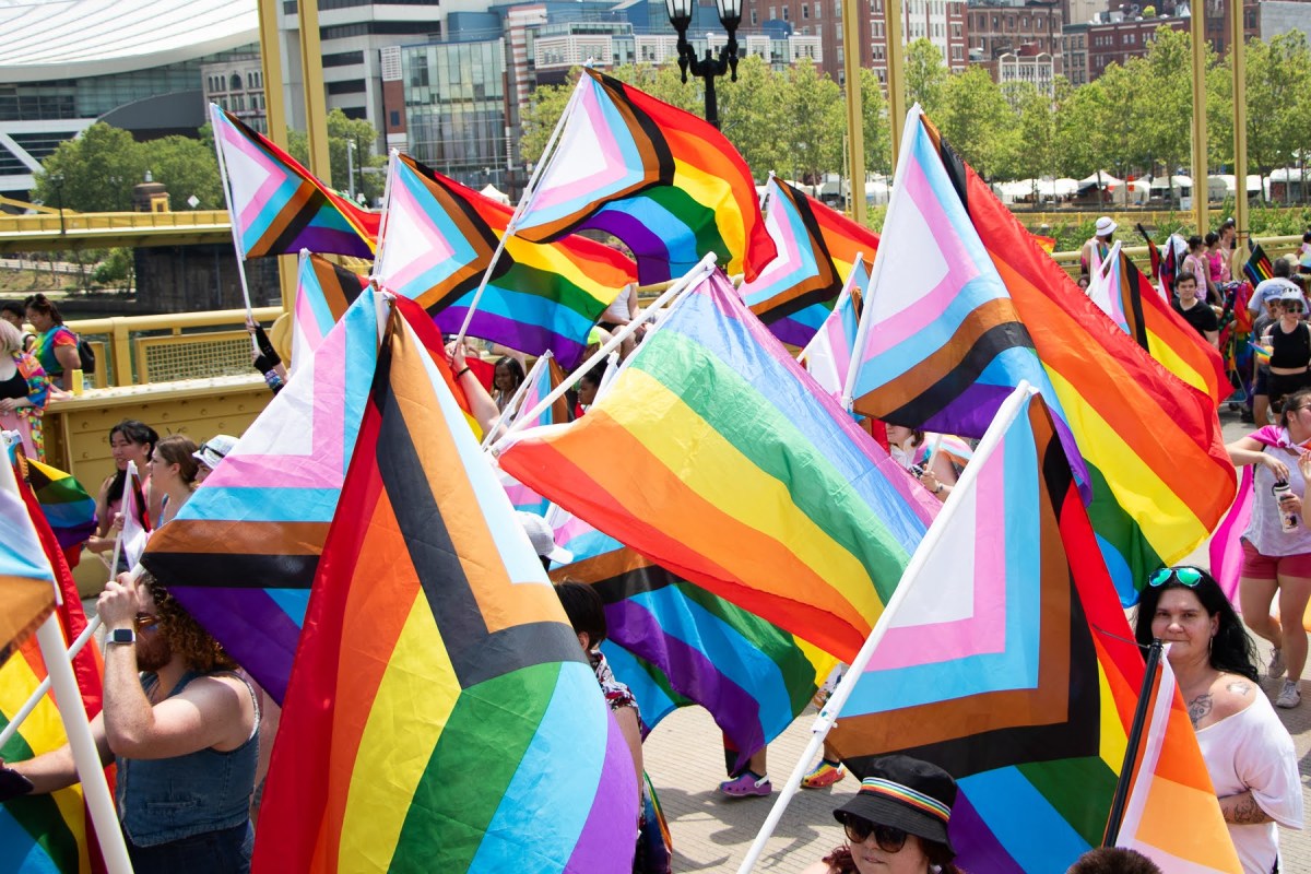 Parade marchers carrying Pride flags walk across the Andy Warhol Bridge toward Allegheny Commons to continue the Pittsburgh Pride Revolution celebration on June 3, 2023.