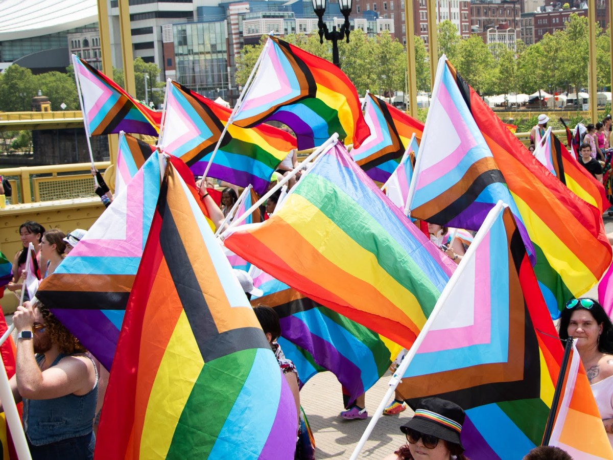 Parade marchers carrying Pride flags walk across the Andy Warhol Bridge toward Allegheny Commons to continue the Pittsburgh Pride Revolution celebration on June 3, 2023.