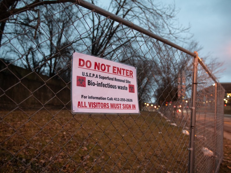 Signs hang on the fence blocking access to the piece of lawn that used to house the Stockton Avenue encampment on Jan. 6, 2023, in Allegheny Center. The camp was swept by the Department of Public Works on Dec. 14, 2022, moving the people living there into other spaces including the newly opened Second Avenue Commons. (Photo by Stephanie Strasburg/PublicSource)