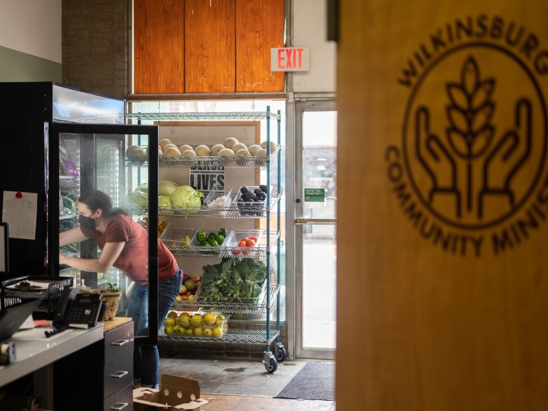 Melissa Wilson stocks a produce refrigerator in between guests at the Wilkinsburg Community Ministry food pantry. Reed has seen an increase in people using the pantry since SNAP benefits were cut back in March. (Photo by Stephanie Strasburg/PublicSource)