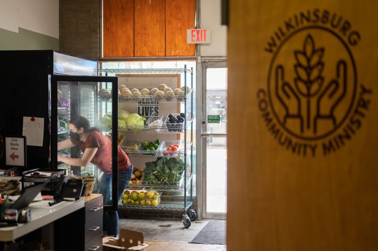 Melissa Wilson stocks a produce refrigerator in between guests at the Wilkinsburg Community Ministry food pantry. Reed has seen an increase in people using the pantry since SNAP benefits were cut back in March. (Photo by Stephanie Strasburg/PublicSource)