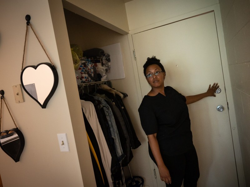 Hi View Gardens resident Bianca Dobbs demonstrates the unreliability of the door to her two bedroom apartment, Thursday, July 28, 2022, in McKeesport. The Hi View resident says she’s worried for the safety of herself and her 11 year old daughter as broken key fob readers mean entry to her building is no longer secure. (Photo by Stephanie Strasburg/PublicSource)